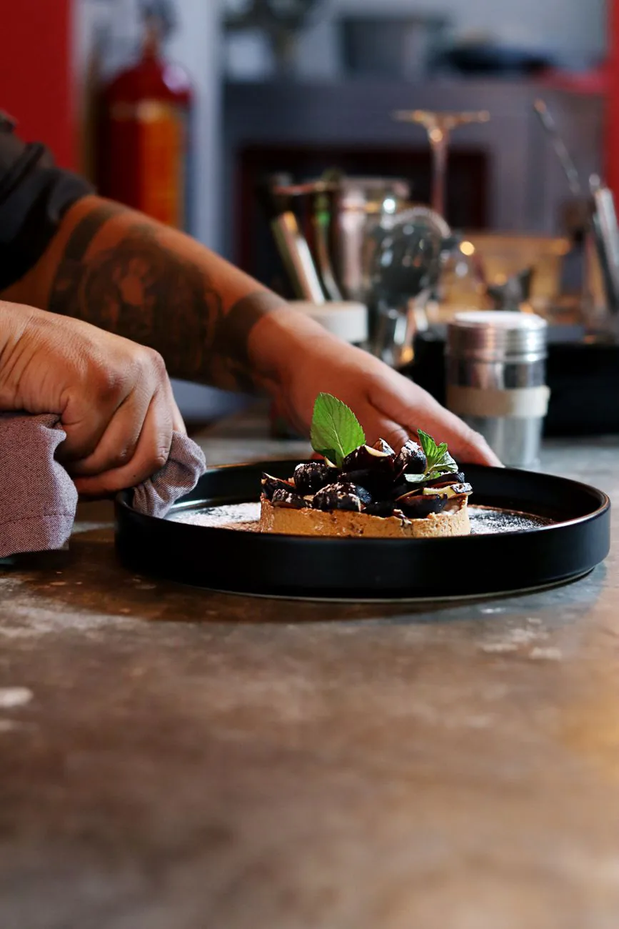 Pastry chef plating a gourmet dessert in a professional kitchen